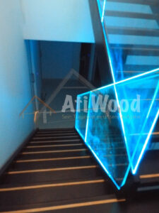 Escalera interior de madera con barandilla de cristal iluminada