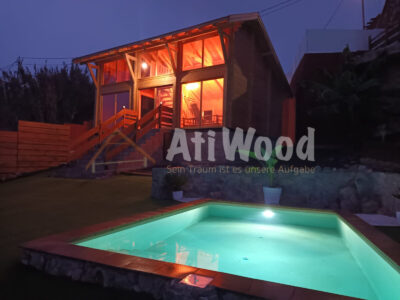 Casa de madera Lyz iluminada por la noche con piscina
